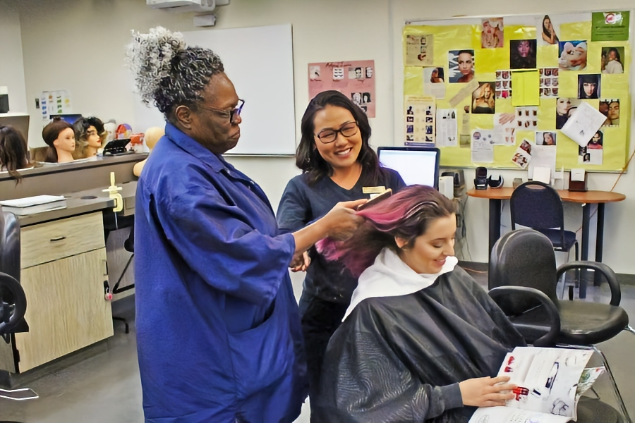 cosmetology instructor demonstrates hair-coloring techniques on a seated student while another student watches in the citrus college salon