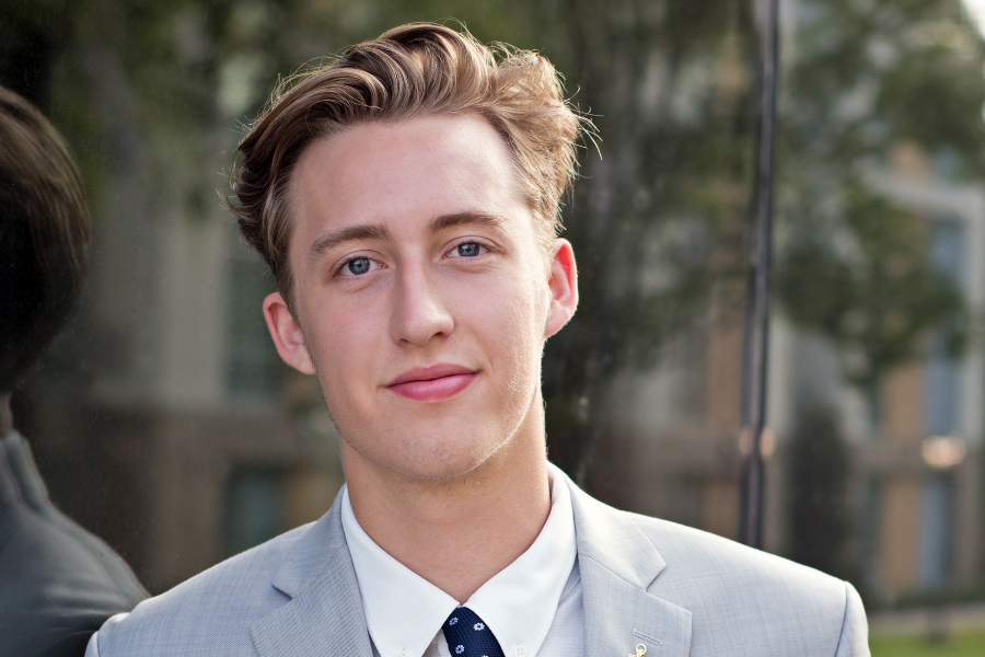 philippe schicker poses outdoors in a light gray suit and tie