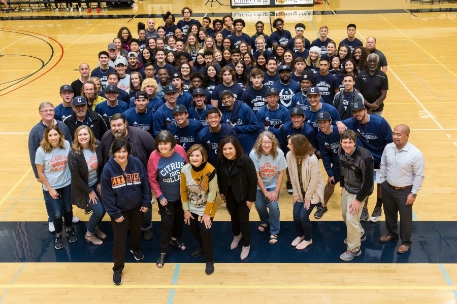large group of citrus college student athletes, coaches and staff pose together on the gymnasium court, with many wearing citrus college athletics shirts, baseball uniforms and other team apparel