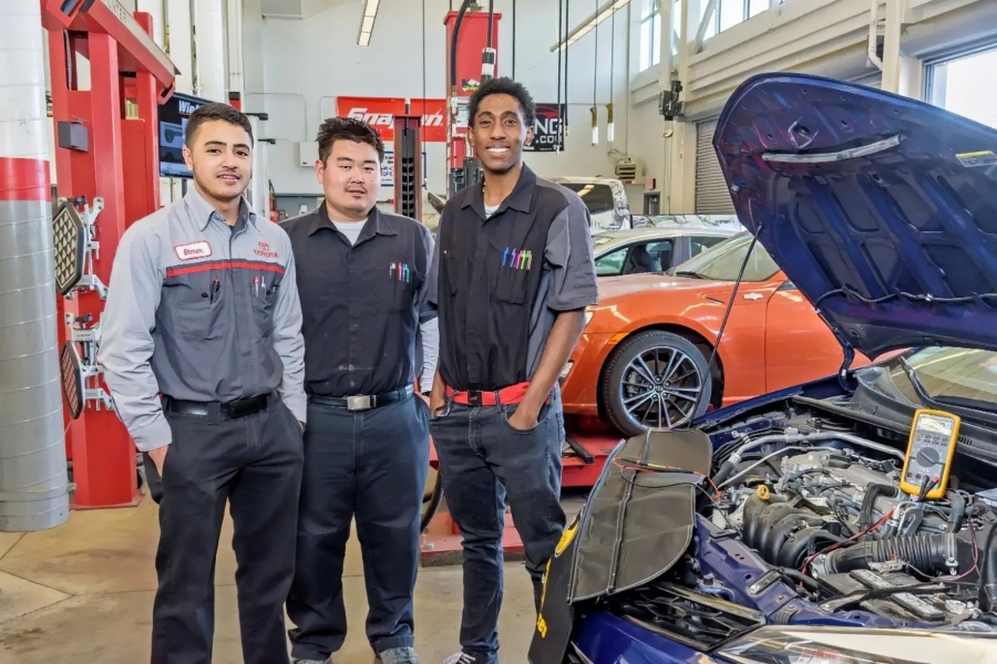 three citrus college automotive technology students stand beside a vehicle with its hood open inside an automotive lab