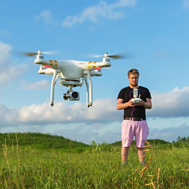 man standing in a field using a drone