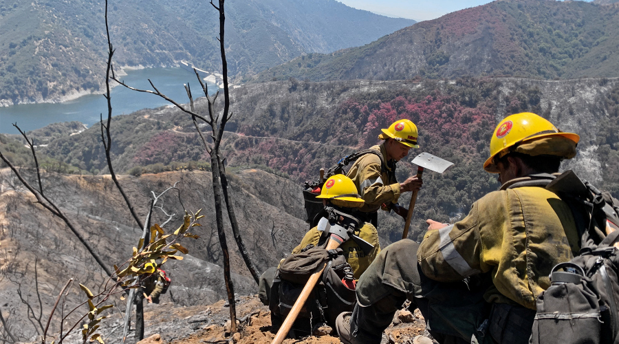 wildland firefighters work on a burned hillside above a reservoir after a fire in azusa canyon