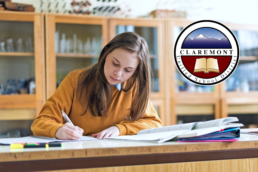 student works on an assignment in a classroom with the claremont unified school district logo displayed above her