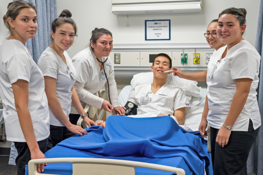 five nursing students practice patient care with a classmate in a simulated hospital room at citrus college