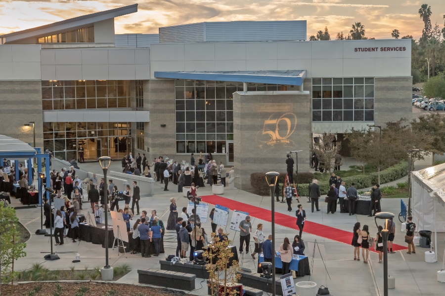 citrus college foundation 50th anniversary guests gather outside the student services building at sunset with a red carpet reception tables and a large illuminated 50th anniversary logo projected on the building facade