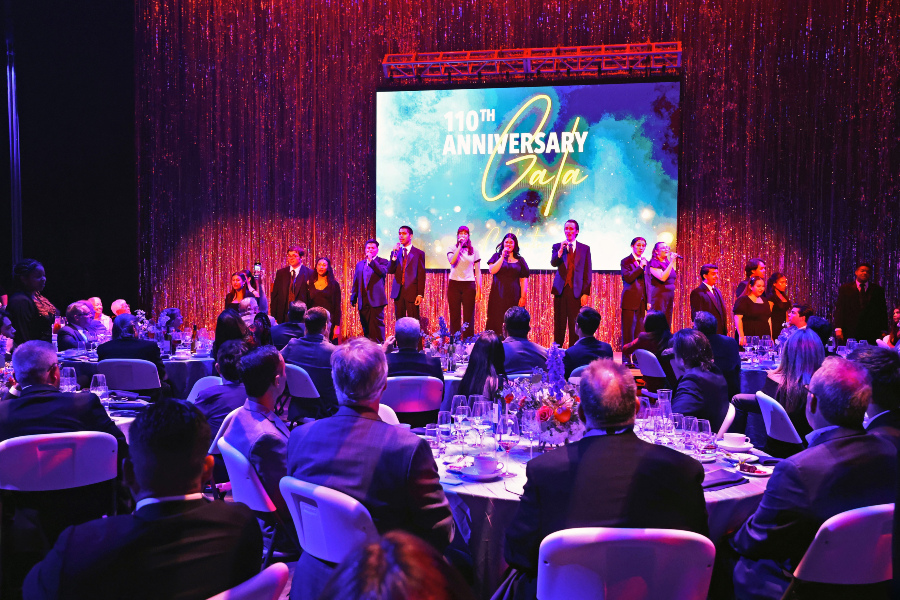 performing arts students sing onstage as guests dine beneath colorful lighting at the citrus college 110th anniversary gala