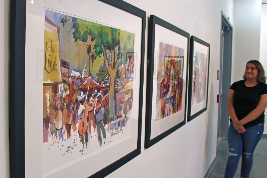 a visitor views framed watercolor paintings by chris van winkle in the citrus college art gallery