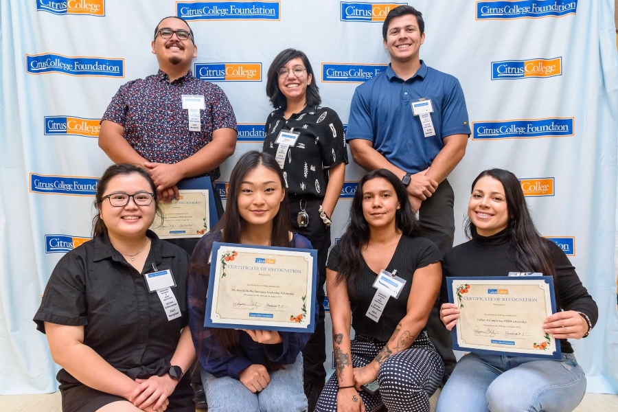 seven citrus college students and staff pose with scholarship certificates in front of a citrus college foundation backdrop during a foundation recognition event