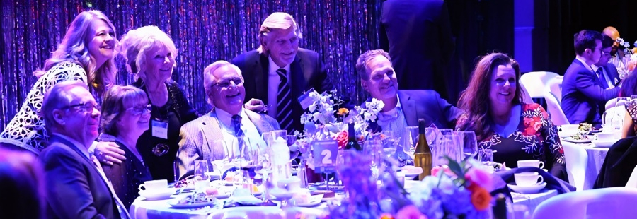 guests smile for a group photo around a decorated table during the anniversary gala