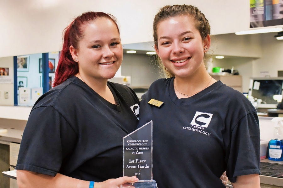 two citrus college cosmetology students smile while holding a first-place avant-garde award from the galactic heroes and villains hair show