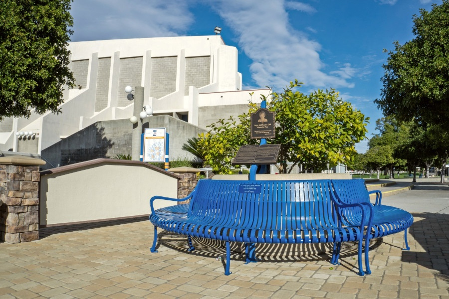 blue circular bench and memorial tree in the citrus college foundation legacy and promise courtyard, with the haugh performing arts center in the background