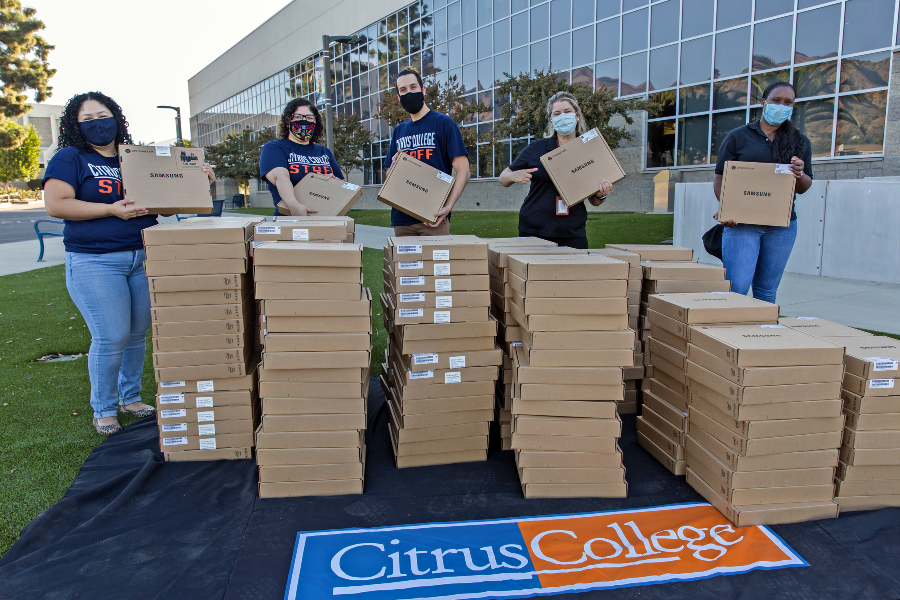 five masked citrus college employees stand behind stacks of boxed chromebooks outside the student services building