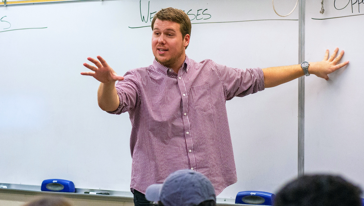 Nick Paulson, a real estate faculty member, standing at a classroom whiteboard, teaches students the skills and knowledge needed to pursue careers in real estate.