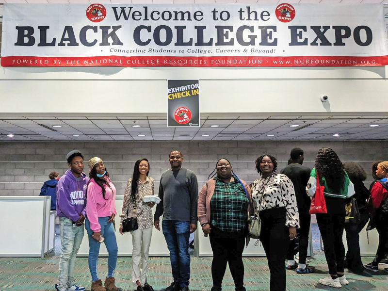 students and staff standing under a Black College Expo welcome banner at a convention center