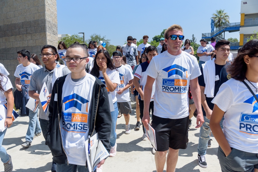 new students wear promise program t-shirts walking into the student services building carrying folders and informational materials