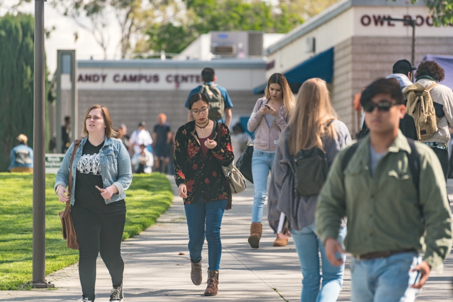 students walk along a campus pathway near the campus center and owl bookshop on a fall morning