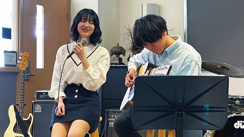 two international students, Izumi and Yuto, singing and playing guitar