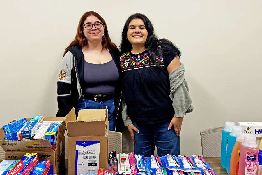 two students stand behind donated toothpaste, toothbrushes, shampoo and other hygiene items collected for the citrus college toiletry drive