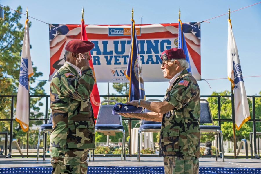 two veterans in uniform conduct a flag-folding ceremony during the saluting our veterans event at citrus college