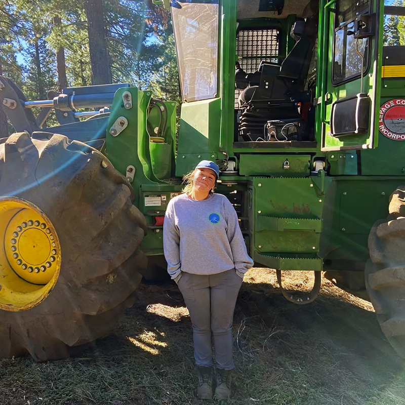 Makena Plourde standing next to a large piece of heavy equipment
