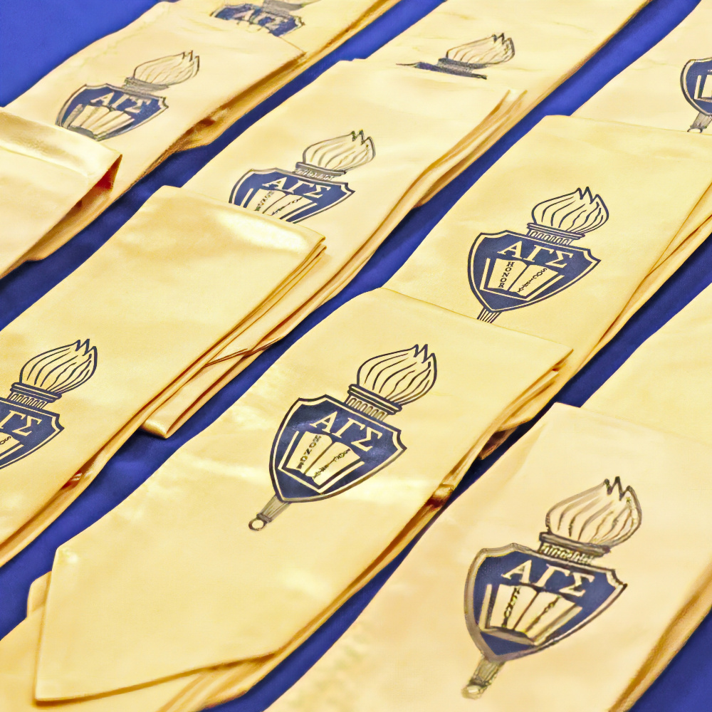 gold alpha gamma sigma honor society stoles arranged on a blue tablecloth