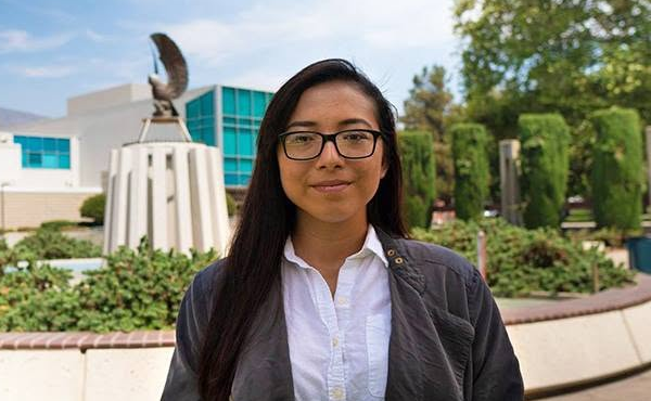 Ivette Ayala standing in front of the owl fountain on campus