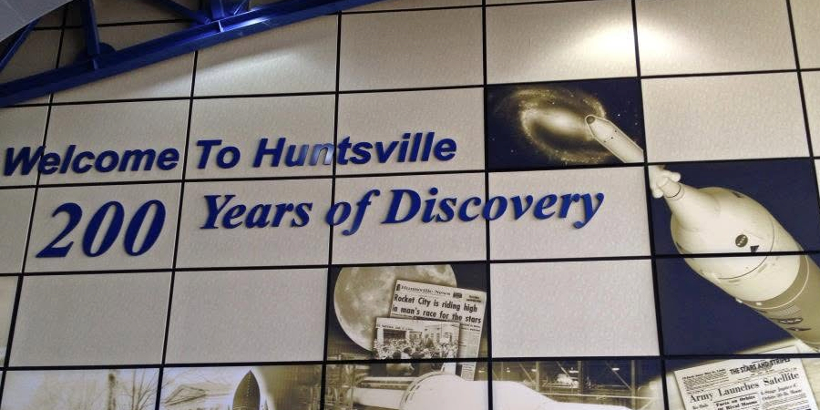 wall display welcoming visitors to huntsville and highlighting "200 years of discovery" with images of rockets, space exploration and historic newspaper clippings