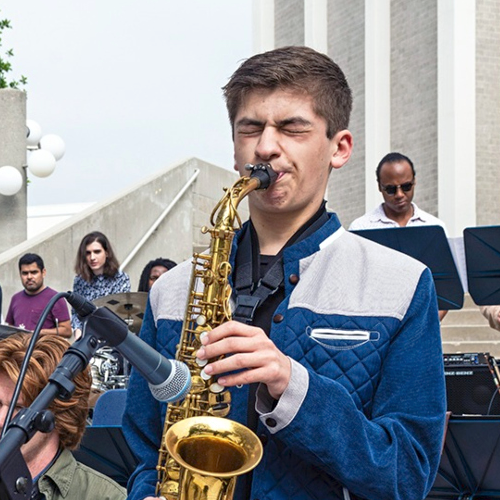 Nathan Palmer playing saxophone on the exterior steps of the Haugh Performing Arts Center with the Blue Note Swing Orchestra